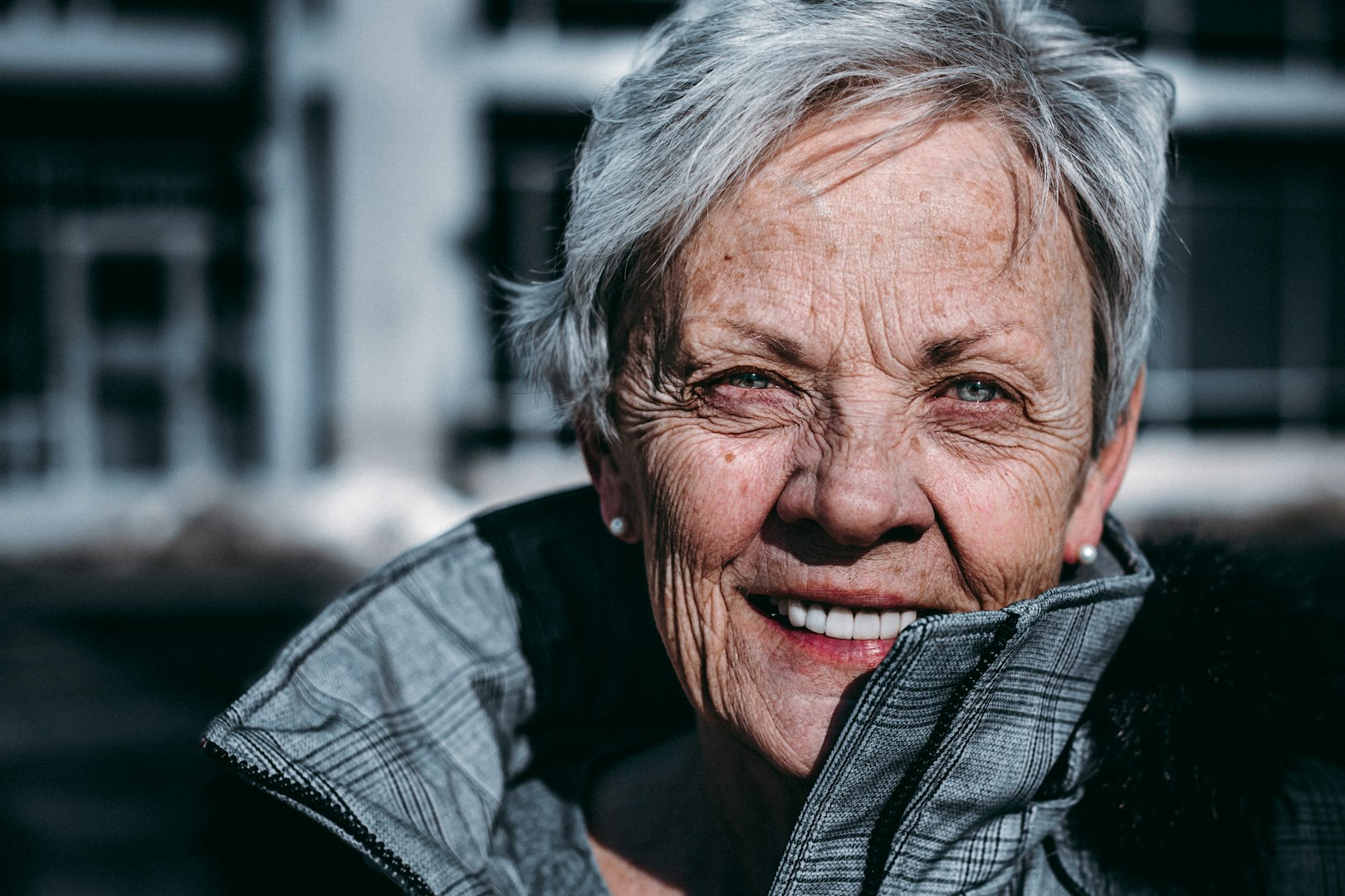 Smiling beautiful audiologist demonstrating proper fitting of a hearing aid device to a senior male customer during a consultation at an audiology center, enhancing communication and quality of life